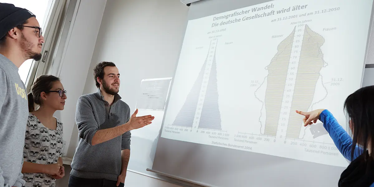 Eine Gruppe Studierender schaut auf eine per Beamer visualisierte Grafik zum demografischen Wandel. Fachbereich Soziale Arbeit der h_da, Hochschule Darmstadt.