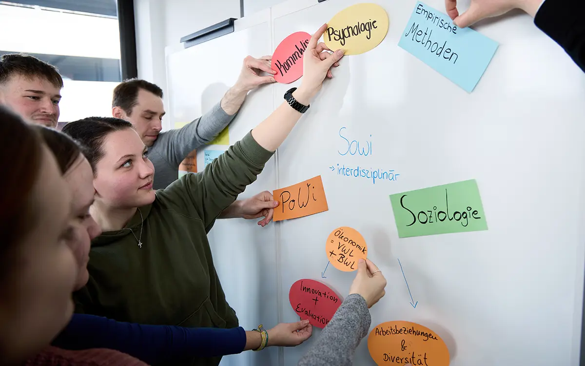  Fachbereich Gesellschaftswissenschaften der h_da, Hochschule Darmstadt, 2 Studierende stehen im Beamerlicht vor einer Grafik