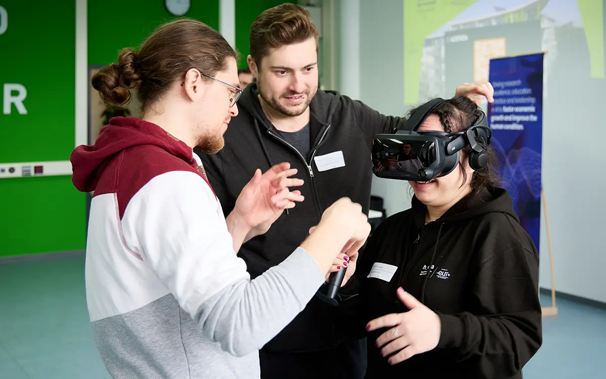 Probandin bekommt eine VR-Brille aufgesetzt. Situation am Fachbereich Informatik der h_da, Hochschule Darmstadt.